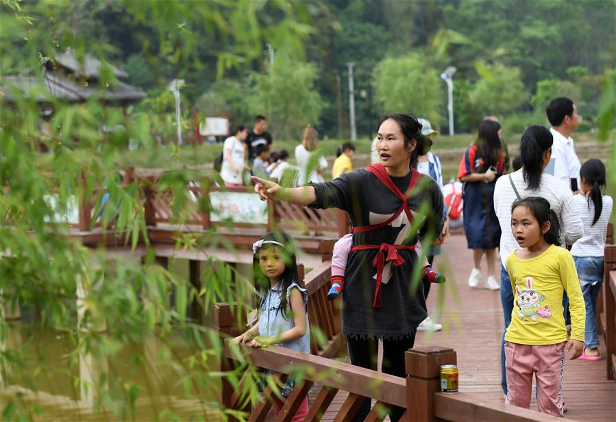 4月19日，在广西南宁市青秀区南阳镇施厚村古岳坡，游客在观看米粉制作。